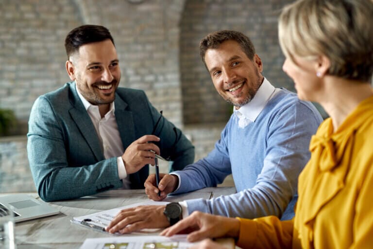 Happy man signing a contract while being with his wife on a meet